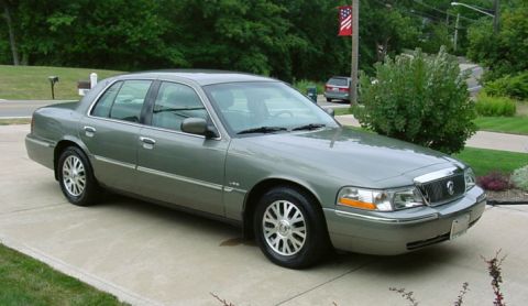 2003 Mercury Grand Marquis - A 2003 Mercury Grand Marquis sedan is seen from a three-quarter front view, parked on a concrete driveway.
