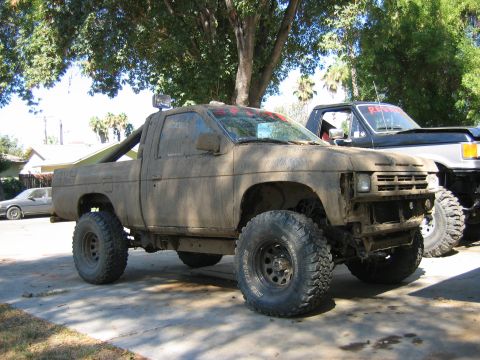 1991 Nissan Pathfinder - This heavily modified pickup truck is covered in mud, suggesting recent off-road use.