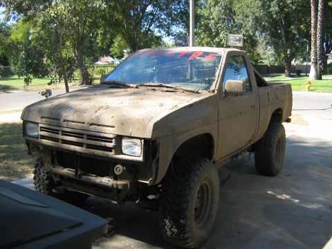 1991 Nissan Pathfinder - This heavily modified pickup truck is covered in mud, suggesting recent off-road use.