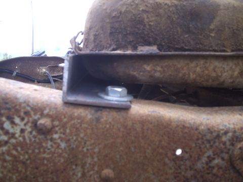 1979 Ford F-150 - Detail of a fuel tank mounting bracket and hardware on a heavily rusted vehicle frame.