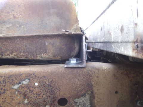 1979 Ford F-150 - This photo shows a close-up view of a fuel tank mounting bracket on a rusty vehicle frame.
