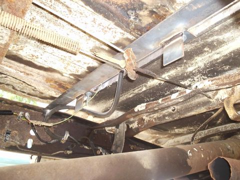 1979 Ford F-150 - Underbody view of a truck, focusing on fuel and brake lines, with visible rust and wooden bed planks.