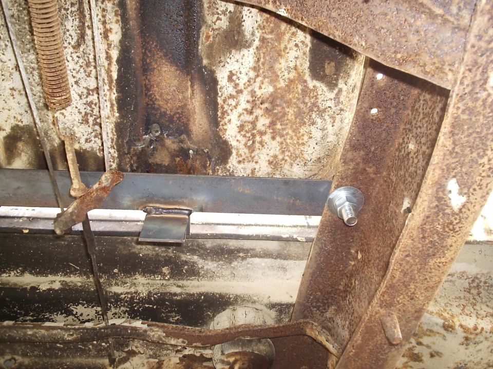 underbody of a rusty vehicle with a metal bracket welded on
