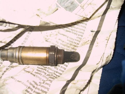 1992 Ford Probe - An oxygen sensor rests on a newspaper, its metallic body showing signs of use.