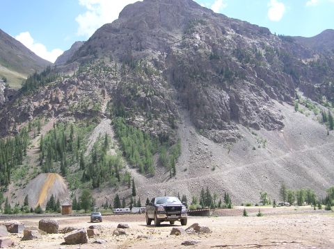 1986 Ford Bronco - A dark pickup truck is parked in a scenic, rocky area with a large mountain in the background.