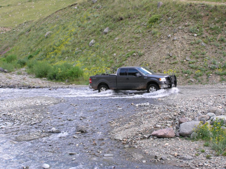 Dark gray pickup truck driving through a stream, 2006 model