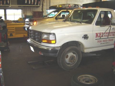 1992 Ford Bronco - A white Ford F-Series truck is parked in a garage, with another vehicle visible behind it.