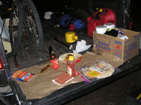 1986 Ford Bronco - A tailgate party is set up with food, drinks, and a bicycle, suggesting an outdoor adventure or event.