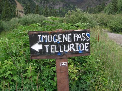 1986 Ford Bronco - Sign for Imogene Pass and Telluride in a mountainous, vegetated area.
