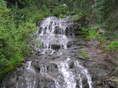 1986 Ford Bronco - Waterfall flowing down rocks in a forest setting, with a Supermotors.net logo visible.