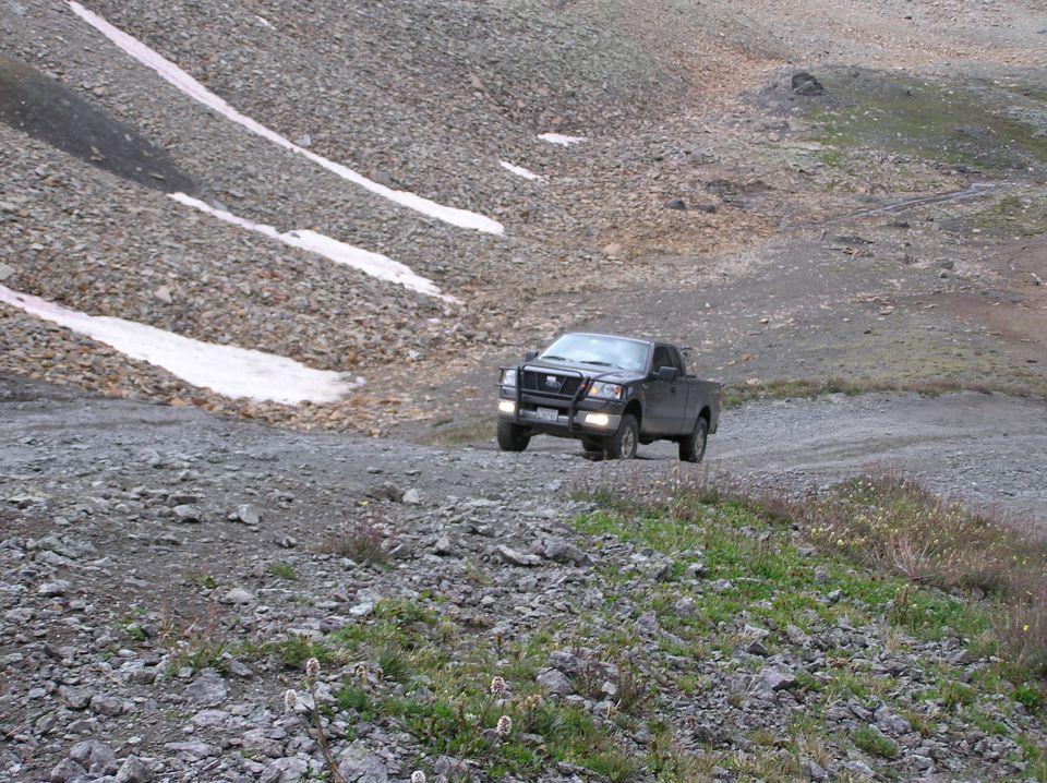 Dark pickup truck on a mountain road, front bull bar visible