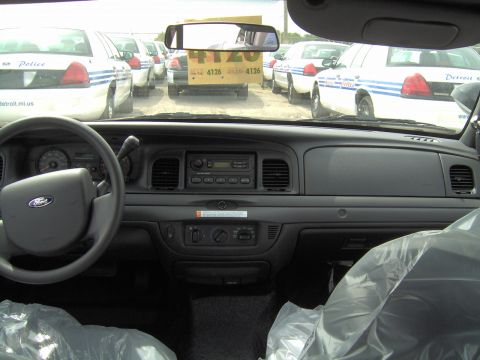 2000 Ford Crown Victoria - Interior of a 2000 Ford Crown Victoria police car, with multiple similar vehicles visible outside.