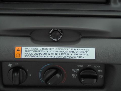 2000 Ford Crown Victoria - Interior view of dashboard controls and a warning label regarding trunk equipment installation.