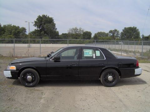 2000 Ford Crown Victoria - Side view of a black police car with temporary bumper coverings and a window sticker.