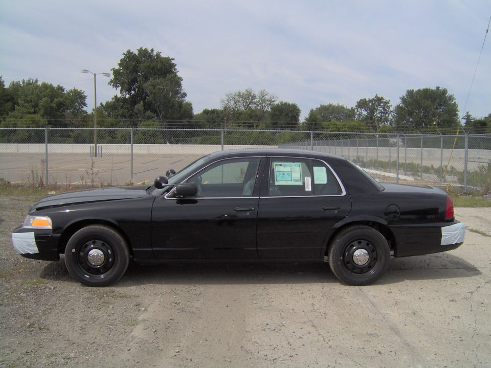 Black Ford Crown Victoria sedan, driver-side profile view with steel wheels
