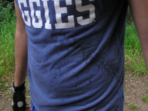 1986 Ford Bronco - A person is shown from the chest down, wearing a blue t-shirt with white lettering and a glove on their left hand.