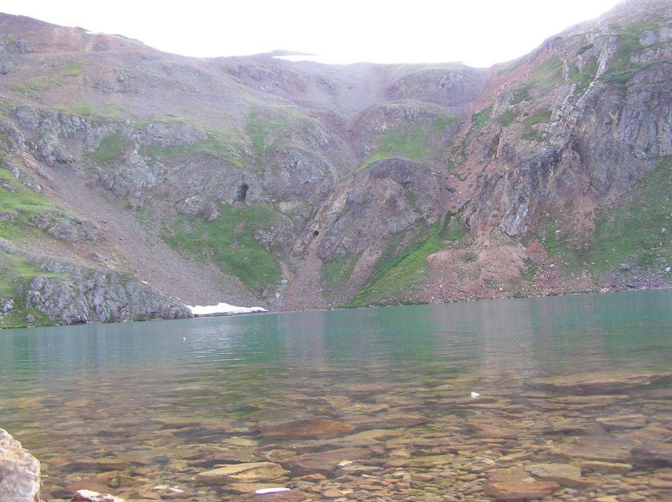 Mountain lake with clear, rocky bottom and steep, vegetated slopes