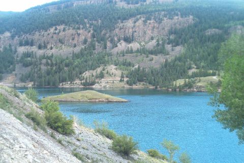 1986 Ford Bronco - Scenic view of a lake with an island and mountains, a Supermotors.net watermark.