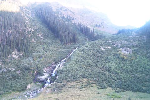 1986 Ford Bronco - A scenic view of a mountain slope with a waterfall, surrounded by dense vegetation.