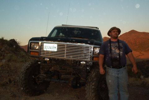 1986 Ford Bronco - A man stands next to a lifted black Ford Bronco in a desert landscape.