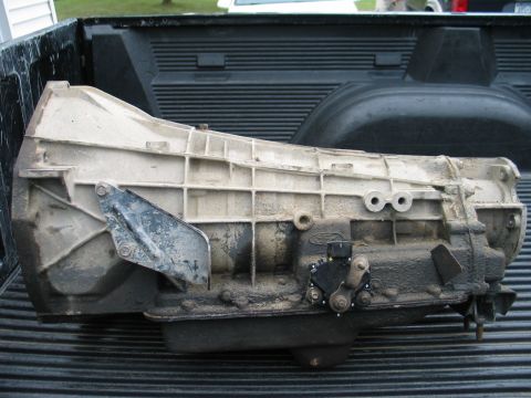 1995 Ford Bronco - A dirty automatic transmission is shown resting in the bed of a pickup truck.