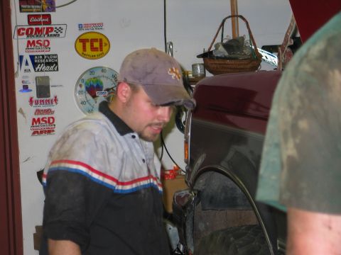 1995 Ford Bronco - A mechanic inspects the side of a 1995 Ford Bronco in a garage setting.