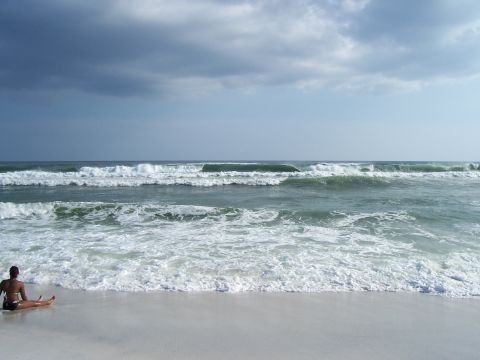 1995 Ford Bronco - A person sits on the sand watching the waves roll in, with the Supermotors logo visible in the corner.