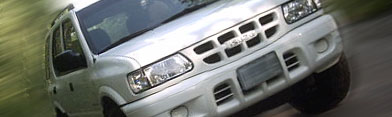 2000 Isuzu Rodeo - The front grille of a silver 2000 Isuzu Rodeo SUV is visible, with motion blur suggesting movement.