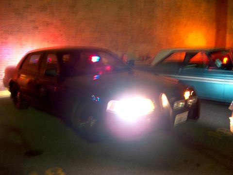 2001 Ford Crown Victoria - Police Crown Victoria with lights on, parked beside another vehicle.