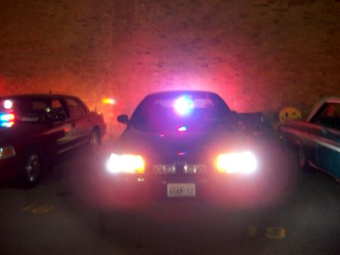 2001 Ford Crown Victoria - Multiple police vehicles are parked together at night, illuminated by their flashing lights.