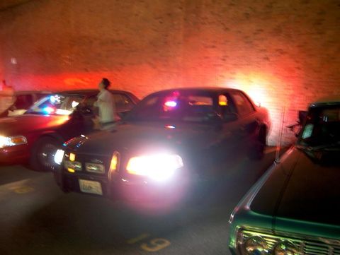 2001 Ford Crown Victoria - Multiple police cars are parked in a dimly lit area with red and blue lights flashing.