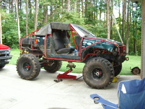 1985 Ford Bronco - This heavily modified off-road vehicle is undergoing maintenance with a visible roll cage and large tires.