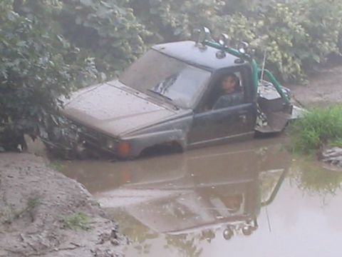 1992 Ford Bronco - Off-road vehicle stuck in a muddy ditch, with water up to the doors.