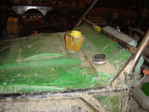 1992 Ford Bronco - Close-up of a green vehicle's hood, showing an exposed air filter and fuel cap, with a roll cage visible.