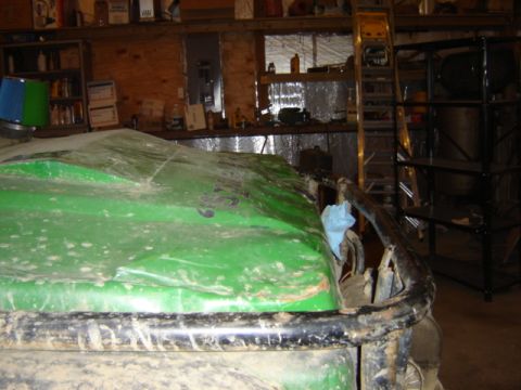1992 Ford Bronco - A green off-road vehicle sits in a cluttered garage, partially covered and showing signs of use.