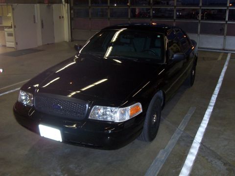 2003 Ford Crown Victoria - black Ford Crown Victoria sedan with blacked-out grille parked in a covered parking garage.