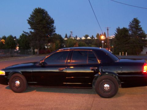 2003 Ford Crown Victoria - A black sedan is parked on the side of the road during dusk.