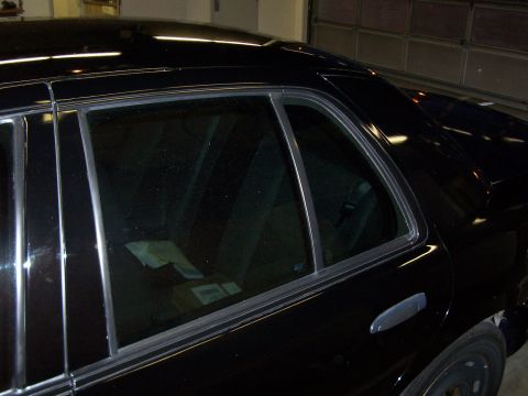 2003 Ford Crown Victoria - The rear passenger side of a black 2003 Ford Crown Victoria sedan is visible, with tinted windows and chrome trim.