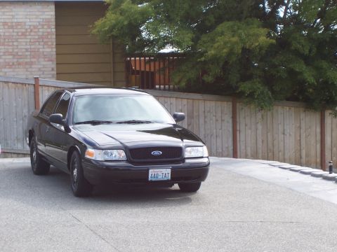 2003 Ford Crown Victoria - Front 3/4 view of a black 2003 Ford Crown Victoria sedan parked outside.