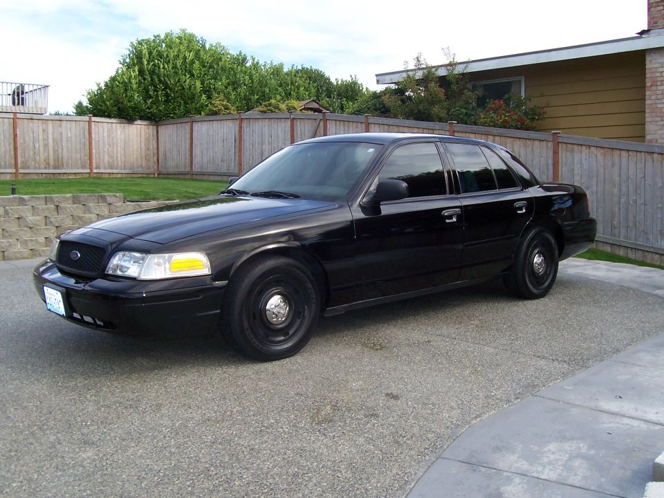 Black sedan parked in a driveway. Looks like a 2003 Ford Crown Victoria