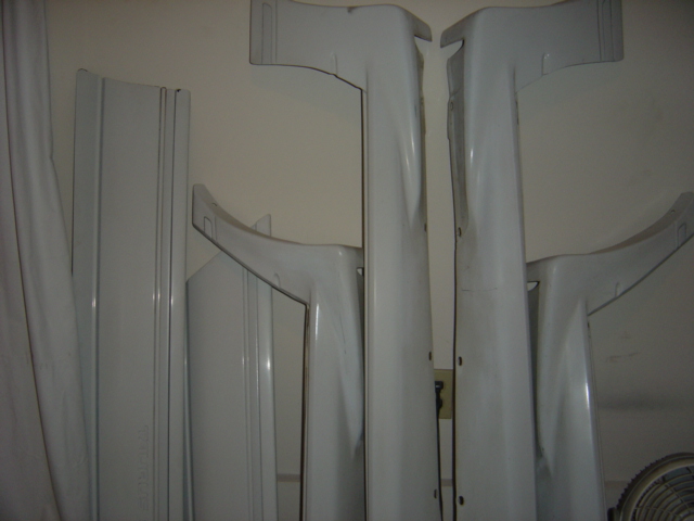 Several white car body kit pieces leaning against a wall