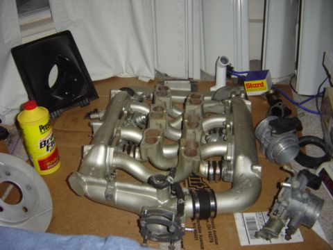 1998 Ford Taurus - Engine intake manifold and associated parts laid out on a cardboard surface.