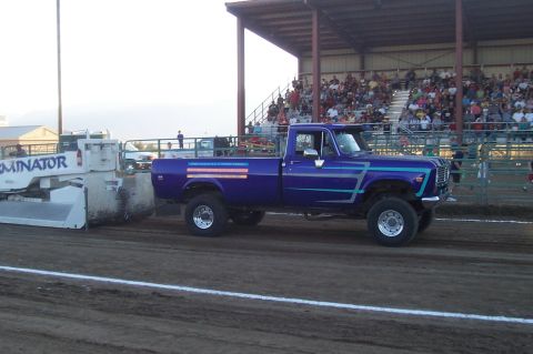 1994 Ford F-150 - A modified pickup truck competes in a pulling event, with spectators in the background.