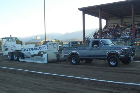 1994 Ford F-150 - A Ford pickup truck tows a large implement at an outdoor event with spectators in the background.