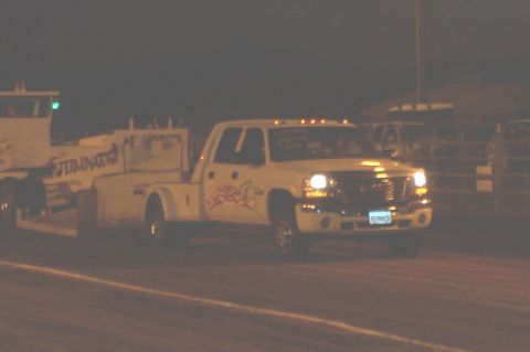 1994 Ford F-150 - A white GMC pickup truck with a tow bed is seen from the front-right angle at night, with another vehicle partially visible to the left.
