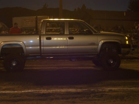 1994 Ford F-150 - A lifted pickup truck is parked on a dirt surface at night, with people visible in the background.