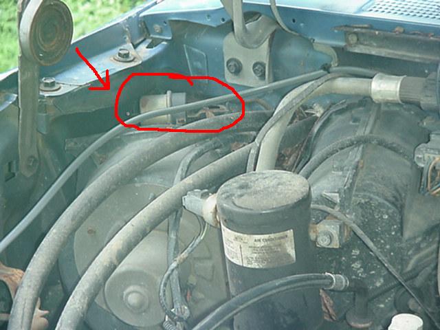 Engine bay with red circle around a component, arrow pointing to bracket