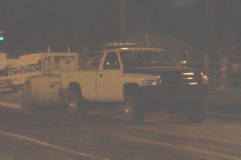 1994 Ford F-150 - A white pickup truck with a black hood is seen on a track, possibly during a race or event.