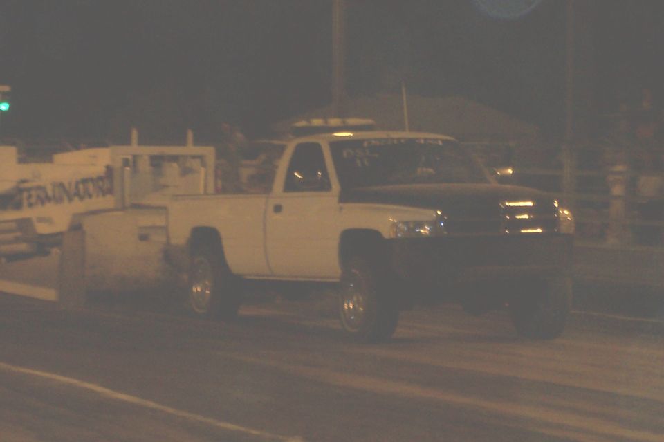 White pickup truck with black hood, possibly a Dodge Ram, on a track
