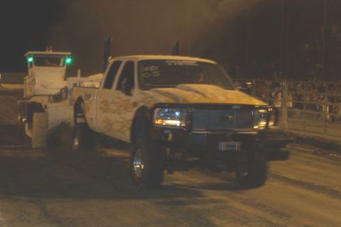 1994 Ford F-150 - A white pickup truck with flame decals and a tow truck are seen at night, with '05' visible on the windshield.